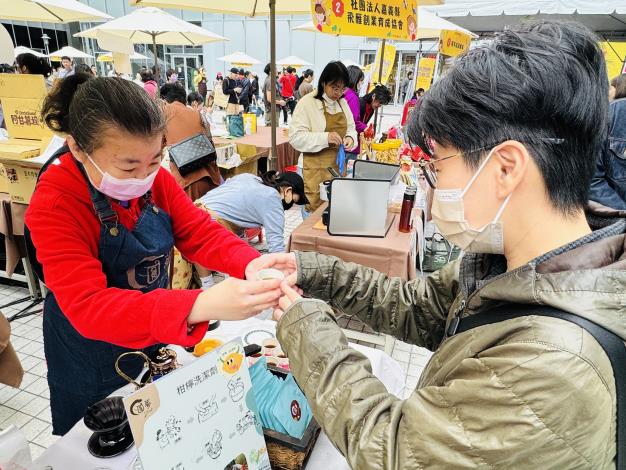 圖3.圓夢庇護工場的小羽努力地叫賣著，展現自信的一面，拿自己的手沖咖啡給民眾試喝。_Instructions for literal